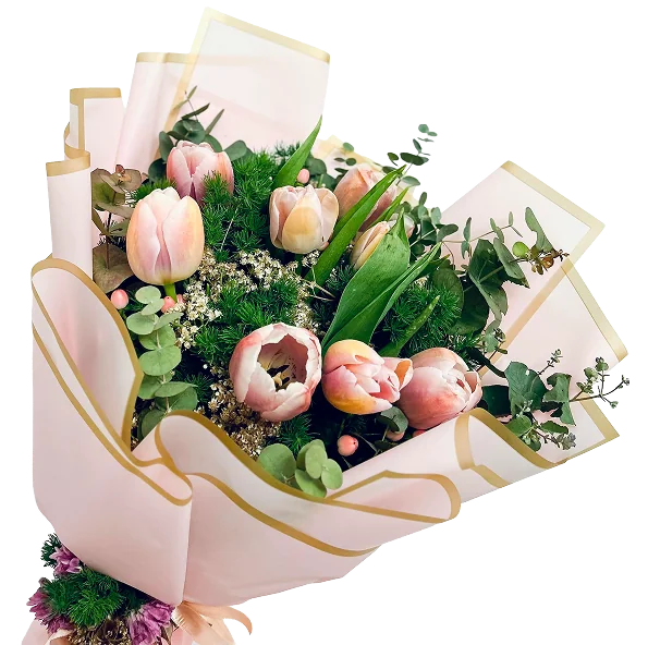 Bouquet de tulipes et renoncules pastel emballé dans un papier rose et doré